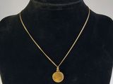 un collier en or avec une pièce de monnaie sur le cou d'un mannequin