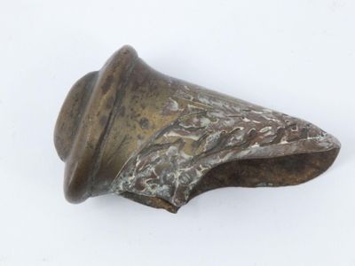 une vieille cloche en bronze posée sur une surface blanche, avec un fond blanc