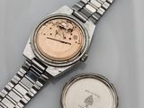 an image of a wrist watch and a coin sitting on a table