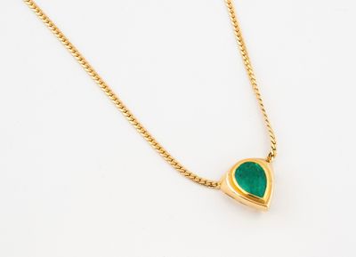 a close up of a gold necklace with a green heart on it