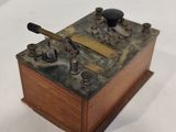 une petite boîte en bois munie d'une poignée en métal, posée sur une surface blanche