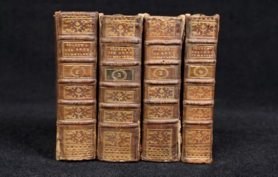 several old books are stacked on top of each other on a black surface