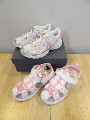 pair of toddler ' s white and pink shoes on a wooden floor