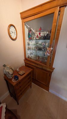 une armoire en bois avec une porte vitrée et une horloge accrochée au mur