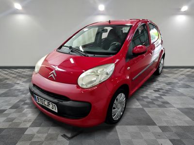 La petite voiture rouge est garée dans le garage, sur le sol à carreaux.