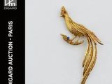 une image représentant une broche en forme d'oiseau en or, avec une pierre bleue dans le bec