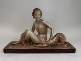 statue en bronze d'une femme assise sur un rocher avec un chien