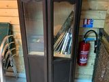 une armoire avec une porte vitrée et une chaise placée devant