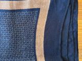 navy blue and tan patterned scarf on a wooden table next to a pair of shoes