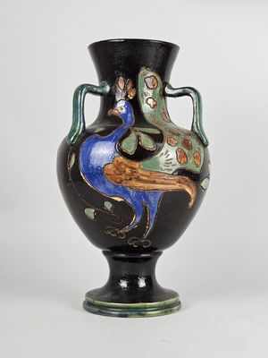a black vase with a peacock on it on a white background