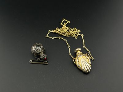 two pieces of jewelry on a black surface with a gold plated necklace