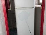 a white refrigerator in the corner of a small room