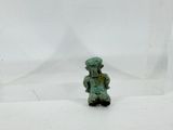 a small figurine of a man sitting on a white surface