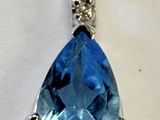 une image représentant un pendentif composé d'une topaze bleue et de diamants, sur fond blanc
