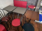 tables and chairs in a restaurant with red seats and a coffee machine