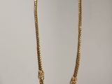 un collier plaqué or avec une chaîne sur fond blanc