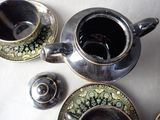 a silver tea pot and two cups on a table