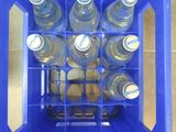bottles of water in a blue plastic crate on a tiled floor
