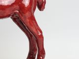 statue of a red horse standing on a rock on a white background