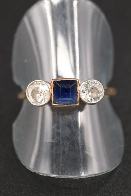 un gros plan d'une bague sertie d'une pierre bleue et de trois diamants