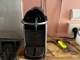 a black coffee maker on a wooden shelf next to a stove