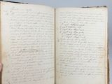 a hand holding an open book with writing on it