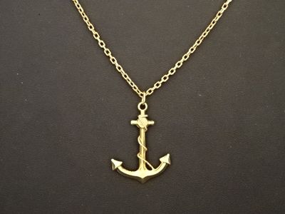 un collier avec une ancre dorée sur fond noir
