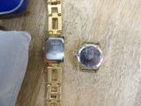 a gold watch and a silver watch on a wooden table