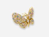 un gros plan sur une broche en forme de papillon ornée de pierres multicolores