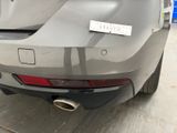 the rear end of a silver car with a sticker on it