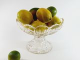 a glass bowl filled with lemons and limes on a table