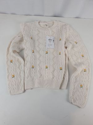 the sweater is white with gold buttons on it