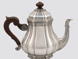 an antique silver teapot with a wooden handle on a white background