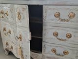 a white dresser with gold decorations on it in a room