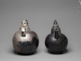 two silver vases sitting on top of a table next to each other