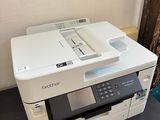 a white printer sitting on top of a black desk next to a wall