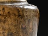 a brown vase sitting on a table with a black background