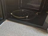 a black microwave oven with a door open on the floor