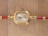 une photo d'une montre-bracelet avec un bracelet rouge et doré
