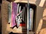 a cardboard box filled with books on a wooden floor