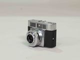 a small silver camera sitting on a white surface