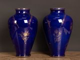 two blue vases with gold designs on them on a table