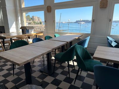 tables and chairs in a room with a view of a body of water
