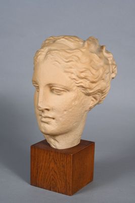 une photo d'une sculpture représentant une tête de femme posée sur un socle en bois