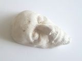 une sculpture blanche représentant le visage d'un homme sur une surface blanche