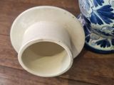 a blue and white vase and a white cup on a wooden table