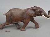 statue of an elephant with tusks and tusks walking on a gray surface