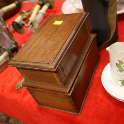 une petite boîte en bois posée sur une table rouge, avec une tasse et une soucoupe