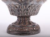 a silver vase with a bird on top of it