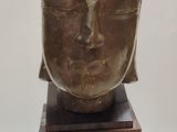 sculpture représentant une tête de Bouddha sur un socle en bois